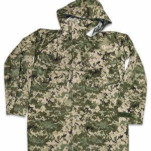 May include: A long-sleeve hooded jacket featuring a digital camouflage pattern in shades of olive green, tan, and black. The jacket includes a front zip closure, two large chest pockets with flaps, and adjustable hook-and-loop cuffs at the wrists.