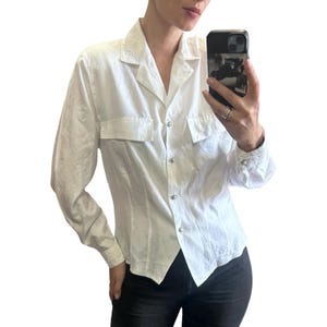 Peut inclure: Chemise blanche boutonnée avec deux poches de poitrine et broderies décoratives sur le col et les poignets. La chemise a une coupe ajustée et est faite d'un tissu texturé. La chemise est boutonnée et a un col classique.