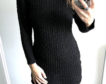 May include: Black mini dress with long sleeves and gold buttons around the neckline.