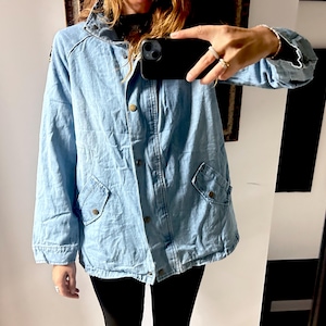 May include: Light blue denim jacket with a button-up front, two front pockets, and a collared neckline. The jacket has a relaxed fit and is made of a medium-weight denim fabric. The jacket is a versatile piece for casual wear.