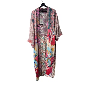 Könnte beinhalten: Lange Patchwork-Kimono-Robe mit einer Vielzahl von Mustern und Farben, darunter Rosa, Rot, Blau und Weiß. Die Robe hängt an einem schwarzen Kleiderbügel vor einem weißen Hintergrund. Die Robe hat ein Blumen- und geometrisches Design.