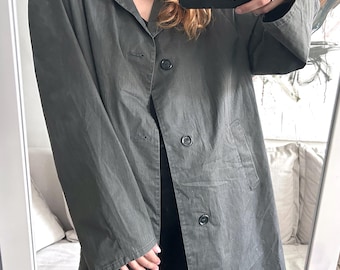 May include: A dark olive green coat with a collared neckline and three visible buttons. The coat has long sleeves and a tailored fit. The image is taken in front of a mirror.
