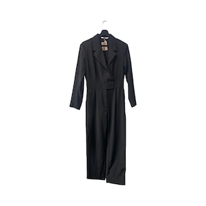May include: A black jumpsuit with a blazer-style top, long sleeves, and wide-leg pants. The jumpsuit is hanging on a black hanger against a white background. A tag is attached to the garment.