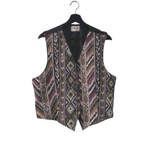 Puede incluir: Un chaleco estampado con cuello y espalda negros, colgado de una percha negra. El chaleco presenta un diseño geométrico en tonos marrones, morados y crema. La marca "ellerse" es visible en el cuello.