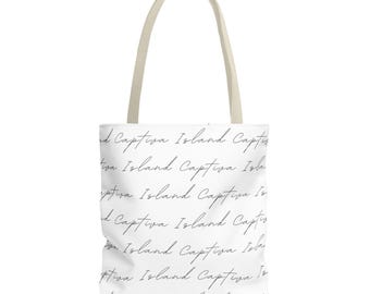 Puede incluir: Un bolso tote blanco con dos asas beige, que presenta un patrón repetitivo del texto Captiva Island escrito en una fuente cursiva negra en toda la superficie del bolso, creando un diseño consistente y legible.