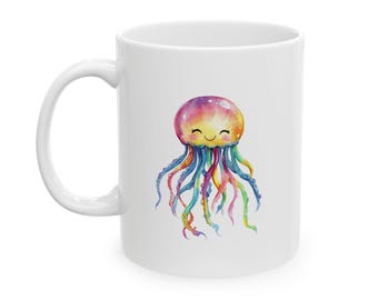 Puede incluir: Una taza de cerámica blanca con una colorida ilustración en acuarela de una medusa sonriente. La medusa tiene una cabeza redondeada con un degradado de rosa, amarillo y naranja, y largos tentáculos fluidos en tonos azules, verdes y morados.
