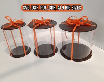 May include: Three clear plastic cylinder boxes with brown lids and orange ribbon bows. The boxes are of different sizes and are arranged in a row from largest to smallest.