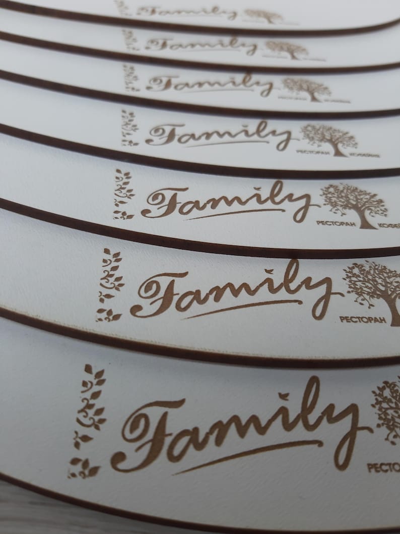 May include: A stack of white coasters with a brown border and the word "Family" in cursive script. The coasters feature a stylized tree design and the word "Restaurant" in Cyrillic script.