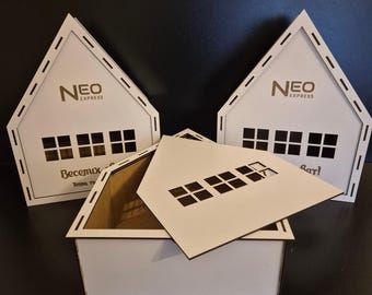 Puede incluir: Tres casas de madera blanca con ventanas recortadas y una base de cartón marrón. Las casas tienen un logotipo que dice "NEO EXPRESS" y el texto "Веселих" y "Eat!" en la parte delantera.