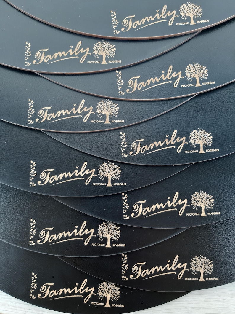 May include: A stack of black leather coasters with a gold-colored logo that says "Family" with a stylized tree and the words "Restaurant" and "Coffee Shop" in smaller font.