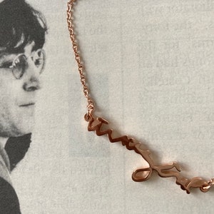May include: A rose gold necklace with a cursive name pendant. The pendant is a delicate, handwritten style.