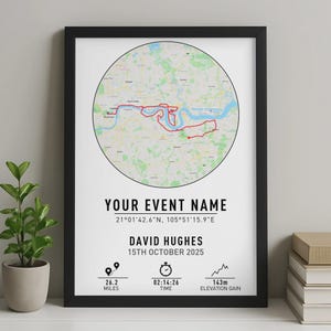 May include: Black framed print with a map of a city, showing a red route within a circular design. Text includes "YOUR EVENT NAME", coordinates, a name, date, and stats: 26.2 miles, 02:14:26 time, and 143m elevation gain.