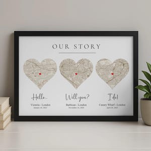 May include: Black framed print with three heart-shaped London map sections. Each heart has a red marker and text: "Hello...", "Will you?", and "I do!" with locations and dates. The title at the top reads "Our Story".