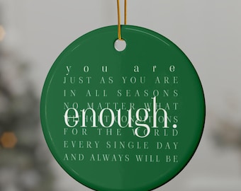 May include: A round, green Christmas ornament with gold string. The ornament has white text that reads "You are just as you are in all seasons no matter what enough. For the world every single day and always will be."