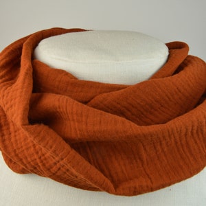 Könnte beinhalten: Ein weicher, rostiger Baumwollschal. Der Schal ist gefaltet und auf einer weißen Puppe ausgestellt.