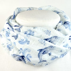 Könnte beinhalten: Ein weißer und blauer Baumwollschal mit einem Muster aus Delfinen und Wellen.