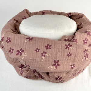Könnte beinhalten: Ein mauvefarbener Infinity-Schal mit einem weißen Blumenmuster. Der Schal ist aus einem weichen, strukturierten Stoff.