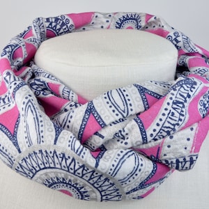 Könnte beinhalten: Ein weißer und rosa gemusterter Infinity-Schal mit einem marineblauen Design. Der Schal ist aus einem weichen, leichten Stoff gefertigt und perfekt, um jedem Outfit einen Hauch von Stil zu verleihen.