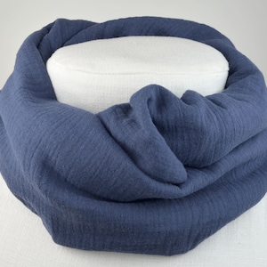 Könnte beinhalten: Ein weicher, blauer Baumwollschal, gefaltet und auf einer weißen Puppe ausgestellt.