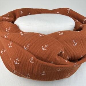 Könnte beinhalten: Ein brauner Baumwollschal mit einem weißen Ankermuster. Der Schal ist gefaltet und auf einer weißen Puppe ausgestellt.