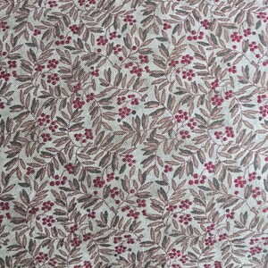 May include: Close-up of a fabric with a repeating pattern of leaves and berries. The leaves are a muted brown, and the berries are a deep red. The background is a light beige color, creating a natural, rustic aesthetic.