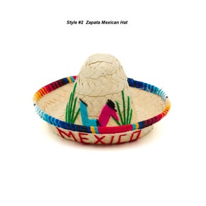 Op de afbeelding: Een strooien sombrero met een kleurrijke band en geborduurde details. De hoed heeft het woord "MEXICO" geborduurd op de rand.