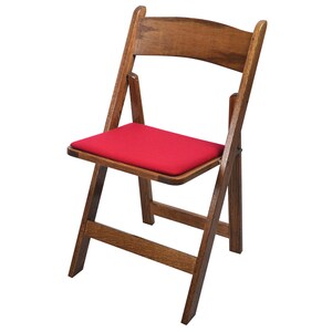 May include: A wooden folding chair with a red padded seat. The chair is made of dark wood and has a simple design.