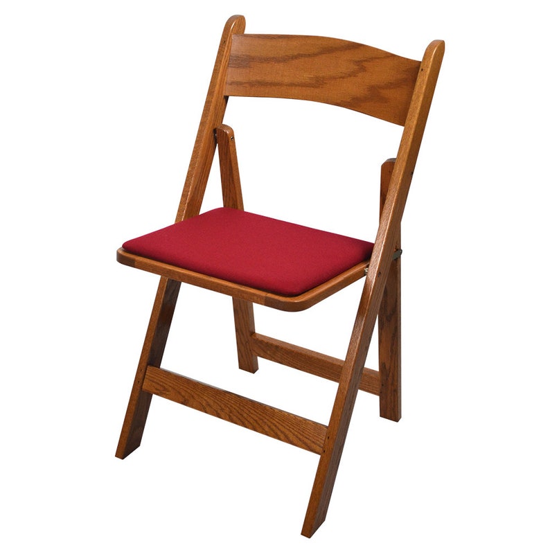May include: A wooden folding chair with a red padded seat. The chair is made of natural wood and has a simple, classic design.
