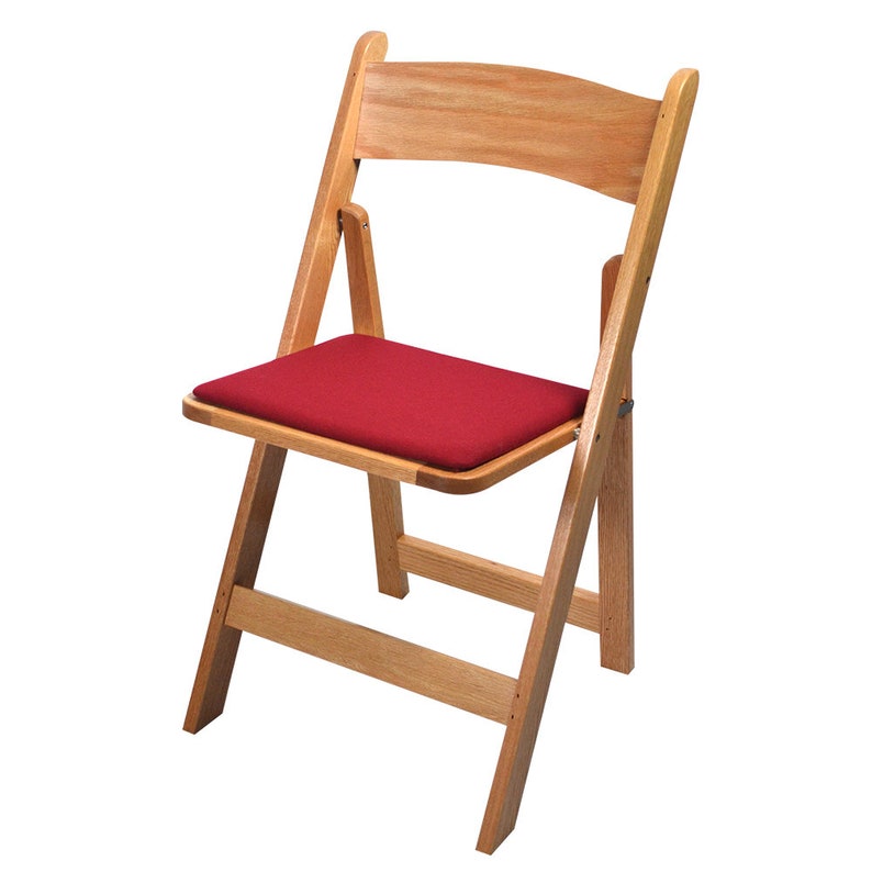 May include: A wooden folding chair with a red padded seat. The chair is made of natural wood and has a simple, classic design.