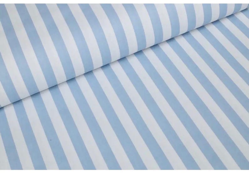 May include: A length of fabric featuring a repeating pattern of vertical stripes in light blue and white. The material is folded over at the top, creating a soft drape that highlights the consistent width and orientation of the alternating color bands.