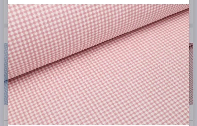 May include: A bolt of fabric featuring a classic light pink and white gingham check pattern. The textile is folded over itself, displaying the consistent small-scale checkered design across the surface of the material in a repeating grid.