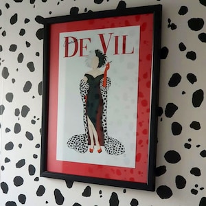 Puede incluir: Una impresi&oacute;n enmarcada de Cruella De Vil de la pel&iacute;cula de Disney 101 D&aacute;lmatas. La impresi&oacute;n presenta una ilustraci&oacute;n en blanco y negro de Cruella con un abrigo de estampado d&aacute;lmata rojo y negro, sosteniendo un cigarrillo. La impresi&oacute;n est&aacute; enmarcada en negro con un passe-partout rojo.
