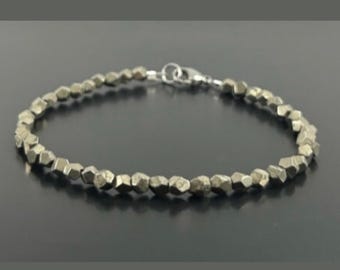May include: A silver bracelet with a chain clasp and a row of small, faceted, metallic gold beads.