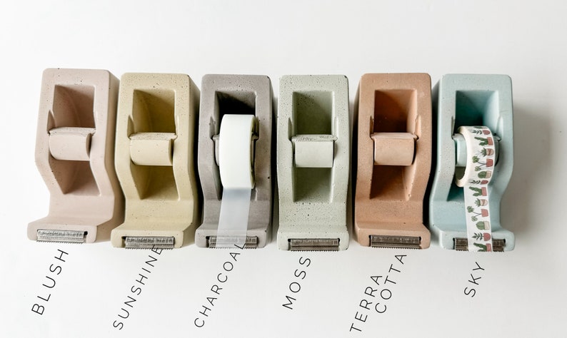 K&ouml;nnte beinhalten: Sechs Beton-Klebebandspender in verschiedenen Farben: Blush, Sonnenschein, Anthrazit, Moos, Terrakotta und Himmel. Jeder Spender hat eine andere Klebebandrolle, darunter transparentes Klebeband, gemustertes Klebeband und Washi-Tape.