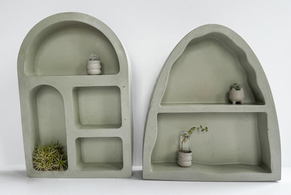 A tiny cast-concrete arch shelf is the kind of brutalist-cute desktop object that makes you stop scrolling — functional micro-sculpture for a plant, crystal, or figurine.
