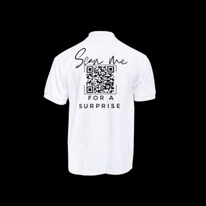 May include: White polo shirt with a black QR code and the text "Scan me for a surprise" printed on the back.