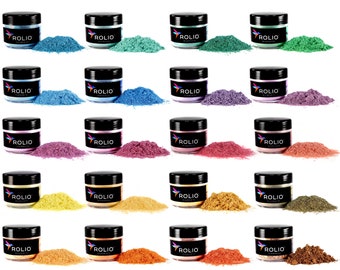 Könnte beinhalten: Eine Sammlung von 24 kleinen Pigmentpulver-Dosen, jede in einer anderen Farbe. Die Dosen sind in vier Reihen mit jeweils sechs Dosen angeordnet. Die Dosen sind mit "ROLIO PIGMENTS" beschriftet.