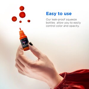 May include: A hand holding a small orange bottle with a black label that says "ROLIO PIGMENTS". The bottle has a dropper tip and is being squeezed to release a drop of orange paint.