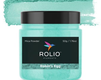 May include: A jar of Robin's Egg Mica Powder by Rolio Pigments. The jar is teal blue and has a black label with the company logo and product name. The label also states "Mica Powder" and "50g / 1.76oz".