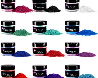 May include: Twelve small jars of pigment powder in various colors, including red, blue, green, black, and white. Each jar has a black lid and a label that reads "ROLIO PIGMENTS".