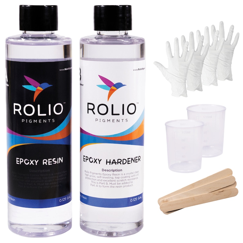 May include: Two clear plastic bottles with white labels, one labeled "Epoxy Resin" and the other "Epoxy Hardener". Both bottles are labeled with the brand name "Rolio Pigments" and contain 0.125 gallons of liquid. The image also shows two clear plastic measuring cups, three pairs of white disposable gloves, and three wooden mixing sticks.