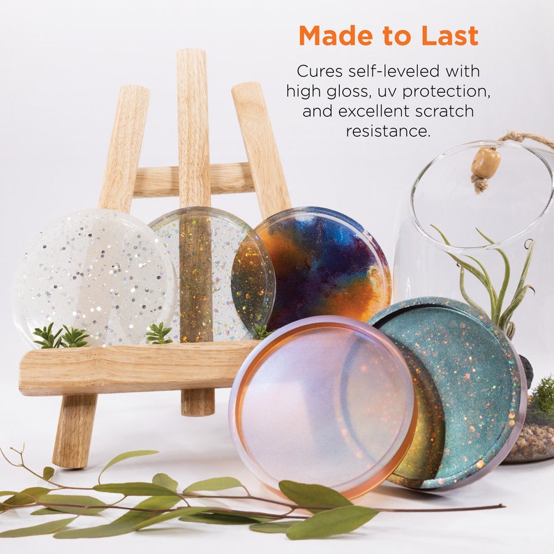 May include: Five round resin coasters in various colors and patterns, including white with glitter, gold glitter, blue and orange swirl, iridescent, and teal with glitter. The coasters are displayed on a wooden easel. "Made to Last" is written in orange text above the coasters. The text below reads "Cures self-leveled with high gloss, uv protection, and excellent scratch resistance."