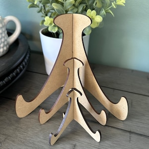 May include: Set of three wooden picture stands in different sizes. The stands are made of brown cardboard and have a triangular shape.