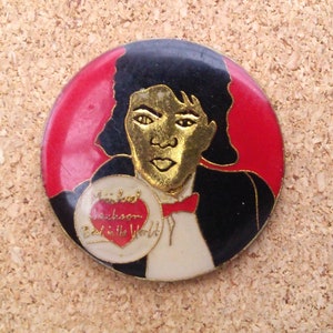 K&ouml;nnte beinhalten: Eine runde Anstecknadel mit rotem, wei&szlig;em und schwarzem Hintergrund. Die Anstecknadel zeigt ein Portr&auml;t von Michael Jackson, der ein Herz mit dem Text "Michael Jackson Best in the World" h&auml;lt.