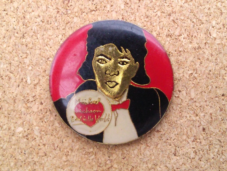 K&ouml;nnte beinhalten: Eine runde Anstecknadel mit rotem, wei&szlig;em und schwarzem Hintergrund. Die Anstecknadel zeigt ein Portr&auml;t von Michael Jackson, der ein Herz mit dem Text "Michael Jackson Best in the World" h&auml;lt.