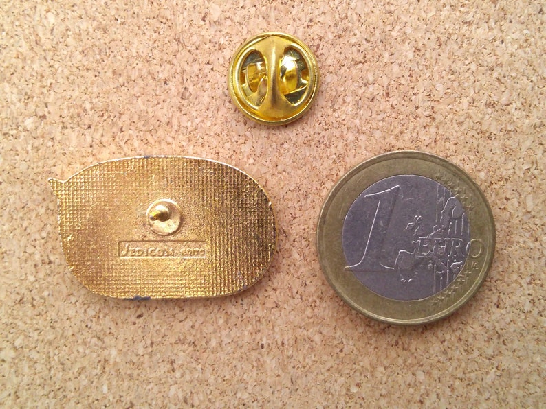 K&ouml;nnte beinhalten: Goldfarbener Metallstift mit einem Cartoon-Bild einer Sprechblase. Die R&uuml;ckseite des Stifts tr&auml;gt den Text "Sedicom 2000".