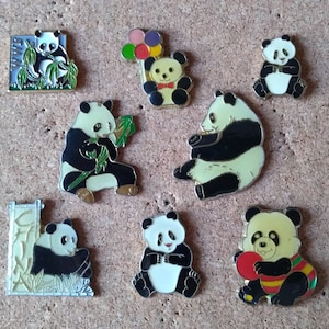 Könnte beinhalten: Eine Sammlung von Panda-Bären-Emaille-Anstecknadeln in verschiedenen Posen. Die Anstecknadeln zeigen schwarz-weiße Pandas, von denen einige Bambus, Luftballons oder einen roten Ball halten. Einige Anstecknadeln haben einen goldenen Rand.