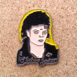 K&ouml;nnte beinhalten: Eine Metallsticker mit einem Portr&auml;t von Michael Jackson mit einem gelben Heiligenschein. Der Sticker ist schwarz-wei&szlig; mit einem silbernen Rand und dem Text "Michael Jackson" unten.