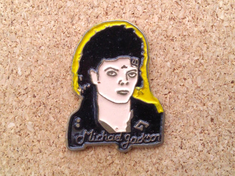 K&ouml;nnte beinhalten: Eine Metallsticker mit einem Portr&auml;t von Michael Jackson mit einem gelben Heiligenschein. Der Sticker ist schwarz-wei&szlig; mit einem silbernen Rand und dem Text "Michael Jackson" unten.