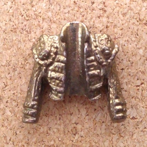 K&ouml;nnte beinhalten: Eine goldfarbene Metalljacke-Anstecknadel mit einem detaillierten Design. Die Jacke hat einen hohen Kragen und einen dekorativen Besatz an den R&auml;ndern.